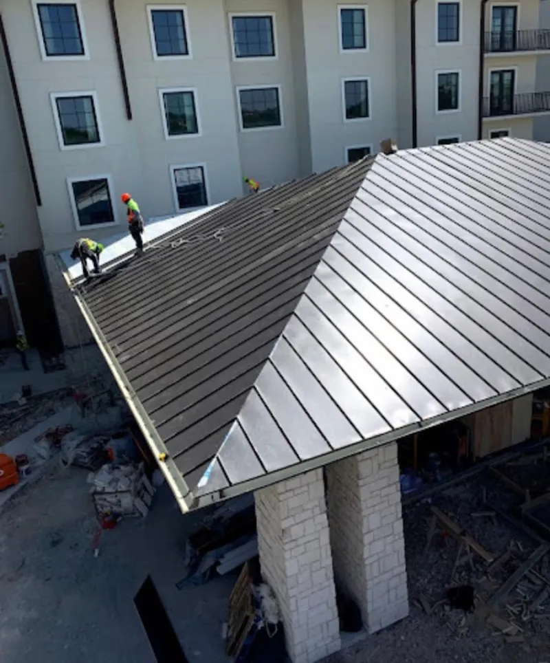 Crew installing standing seam metal roof panels on a commercial project in Sturgis
